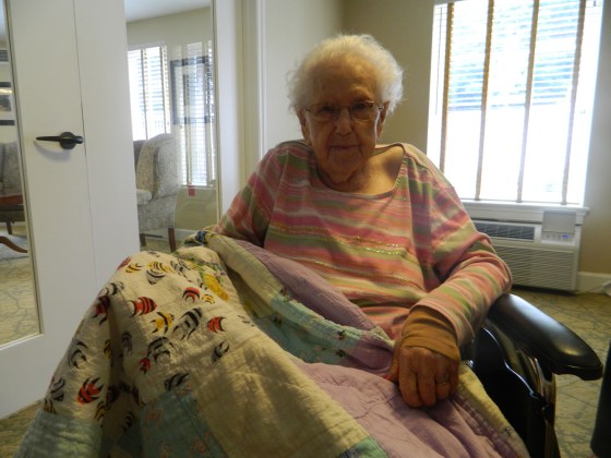 110 year-old Sina Hayes takes a break after eating breakfast in the meeting room at Brookridge Retirement Community in Winston-Salem, N.C. She displays one of her favorite quilts she has made over the years.Credit Keri Brown